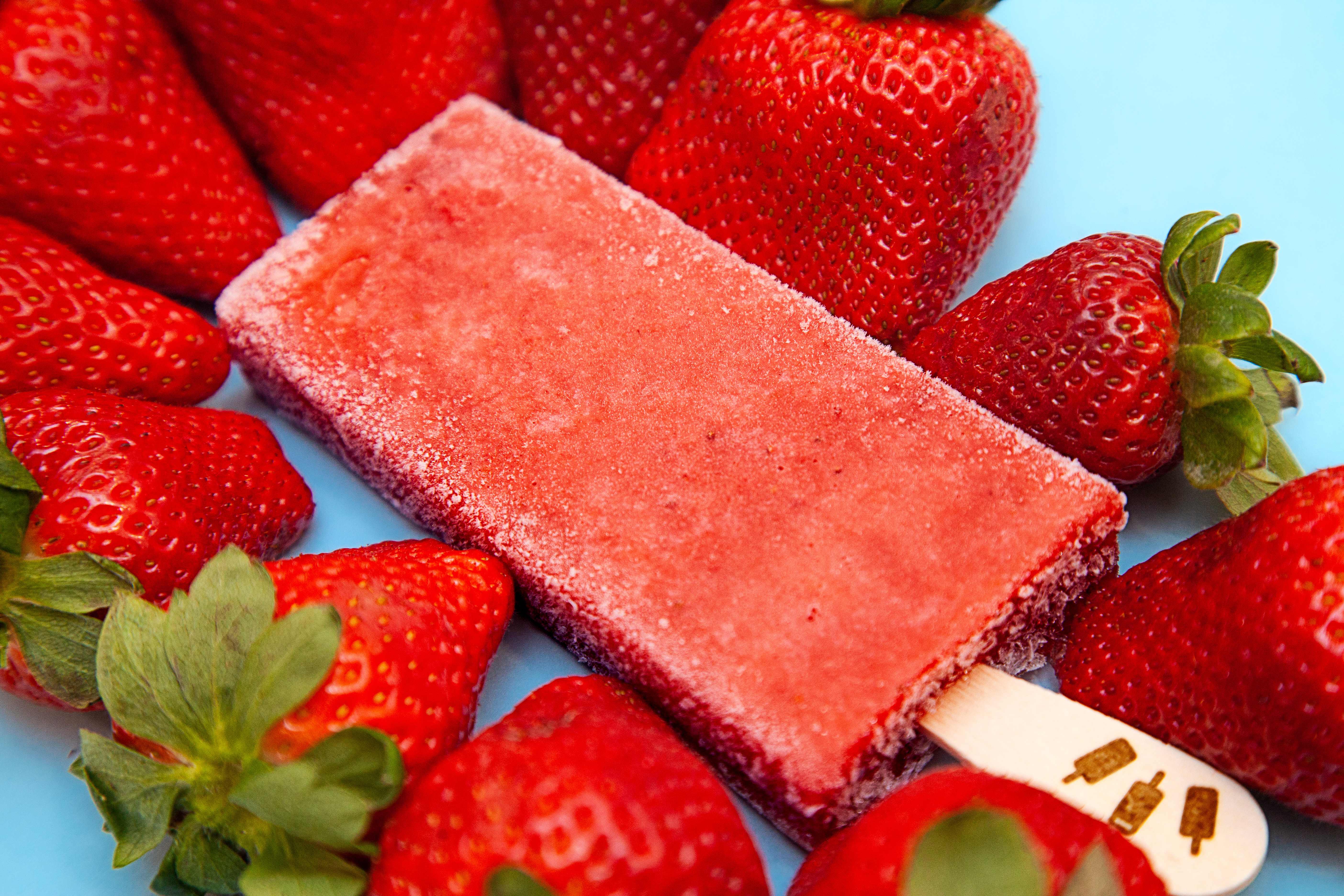 Paleta fraise artisanale entourée de fraises fraîches